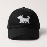 A black baseball cap featuring a white embroidered silhouette of a dog on the front, set against a plain light gray background.