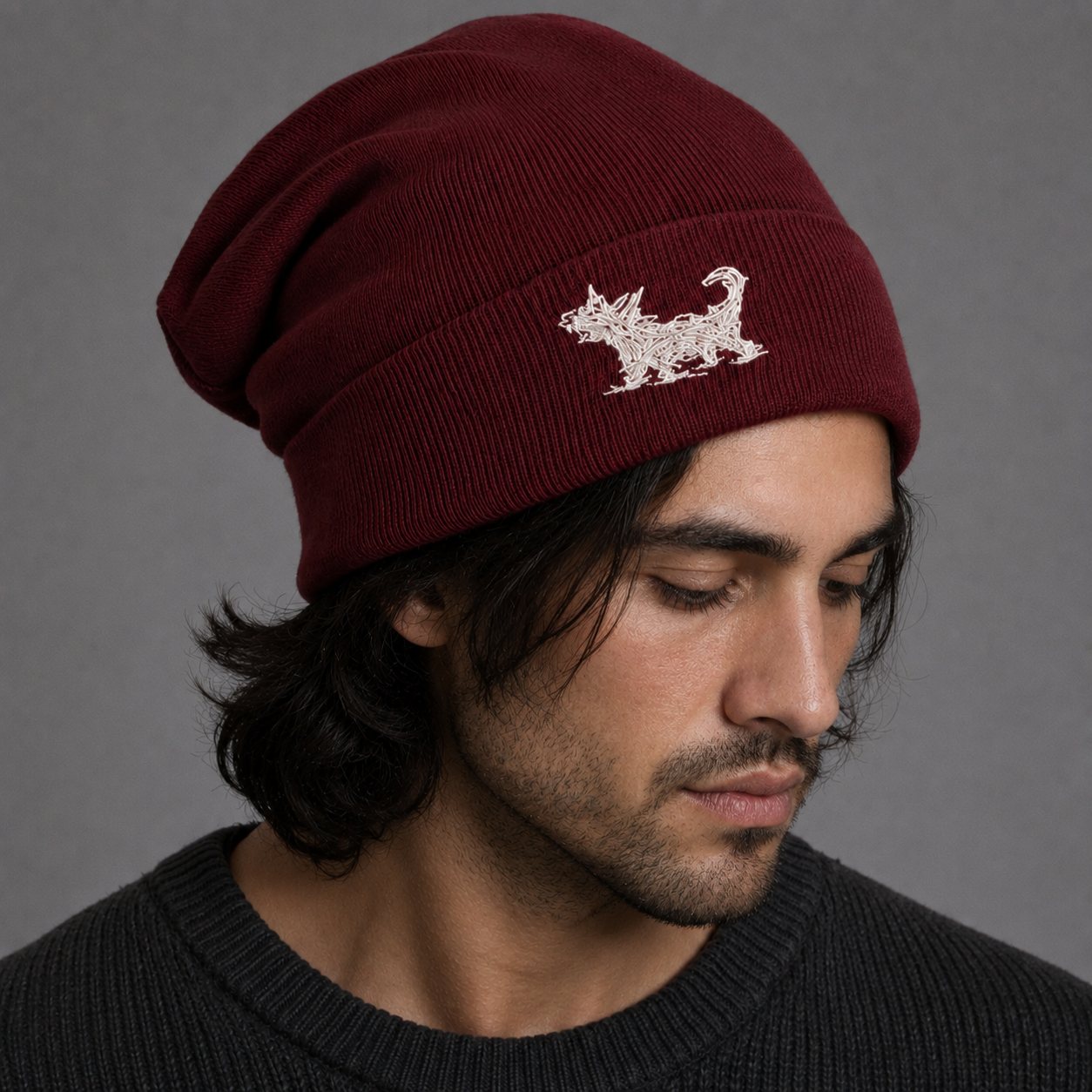 A man wearing a dark maroon ribbed knit beanie with a white embroidered Beans logo on the front, set against a plain gray background.