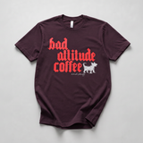 A dark maroon short-sleeve t-shirt with a graphic print reading 'bad altitude coffee' in red gothic font, accompanied by a white dog illustration and the brand name 'animal party' in white script. The shirt is laid flat on a light gray background.